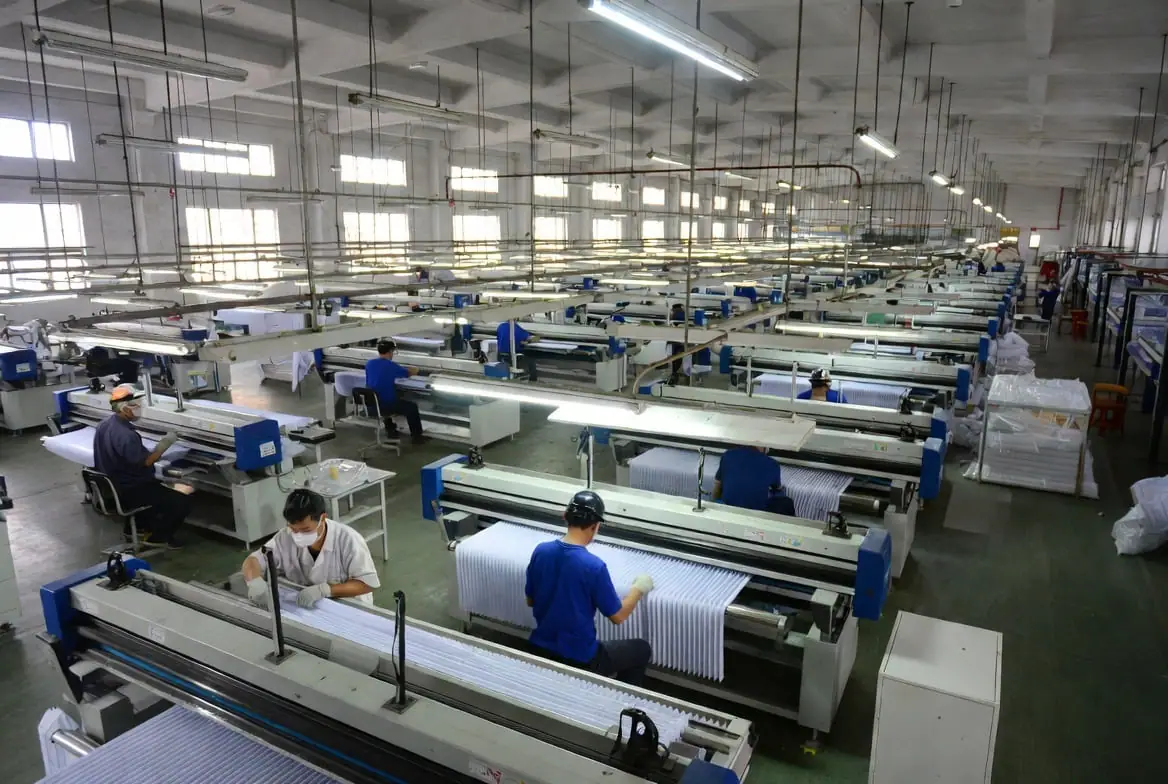 Long rows of pleating and inspection machines on the CAIC factory floor