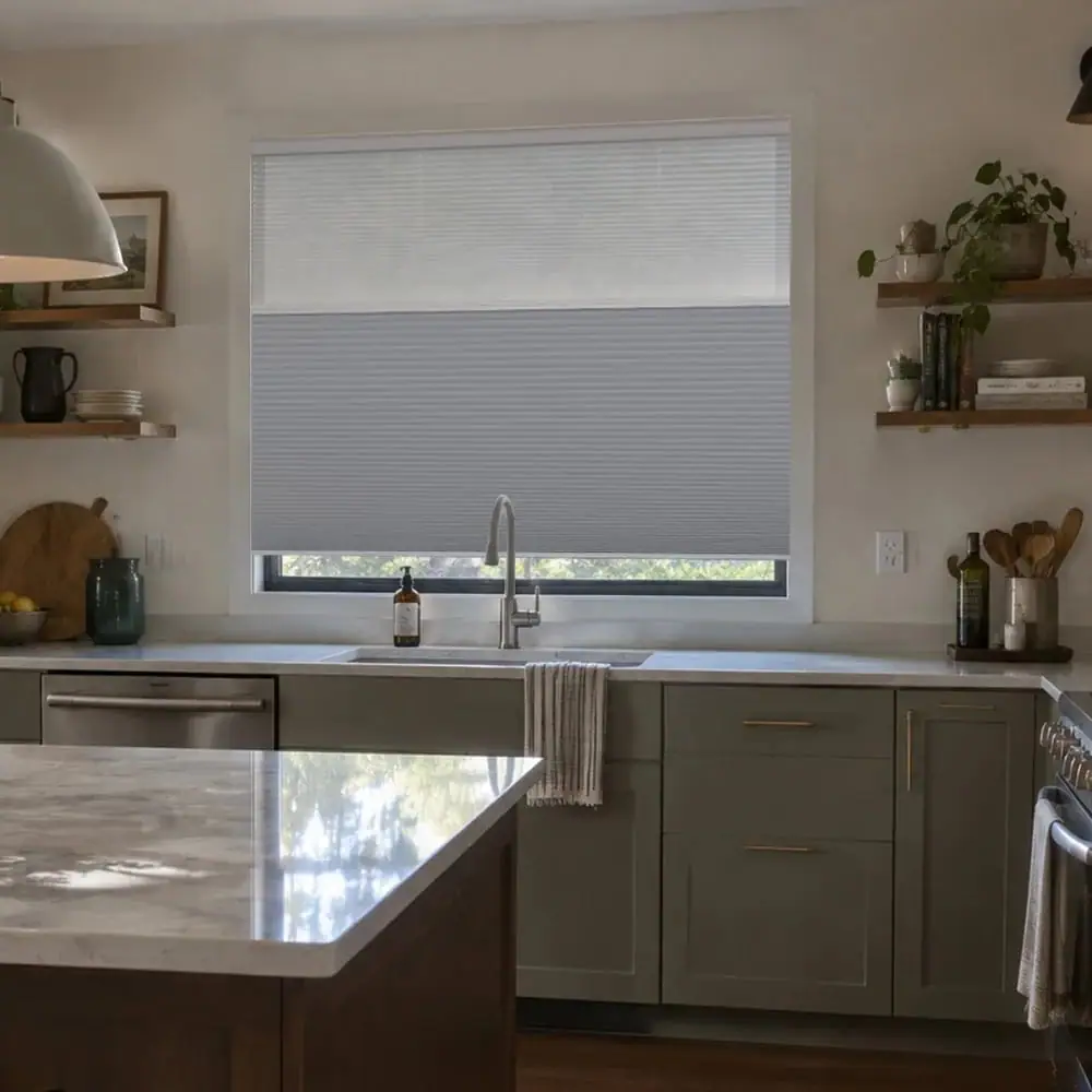Day-night cellular shade lowered halfway over a kitchen window