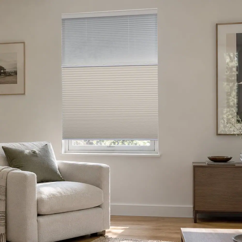 Day-night cellular shade with a sheer upper panel and a light-filtering lower panel above a reading chair